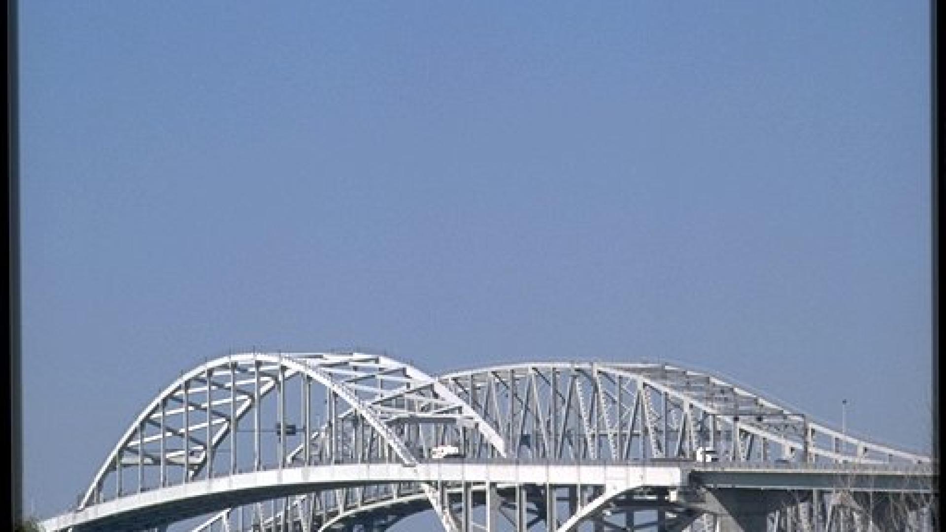 White bridge standing tall. The sky is blue behind the bridge. 