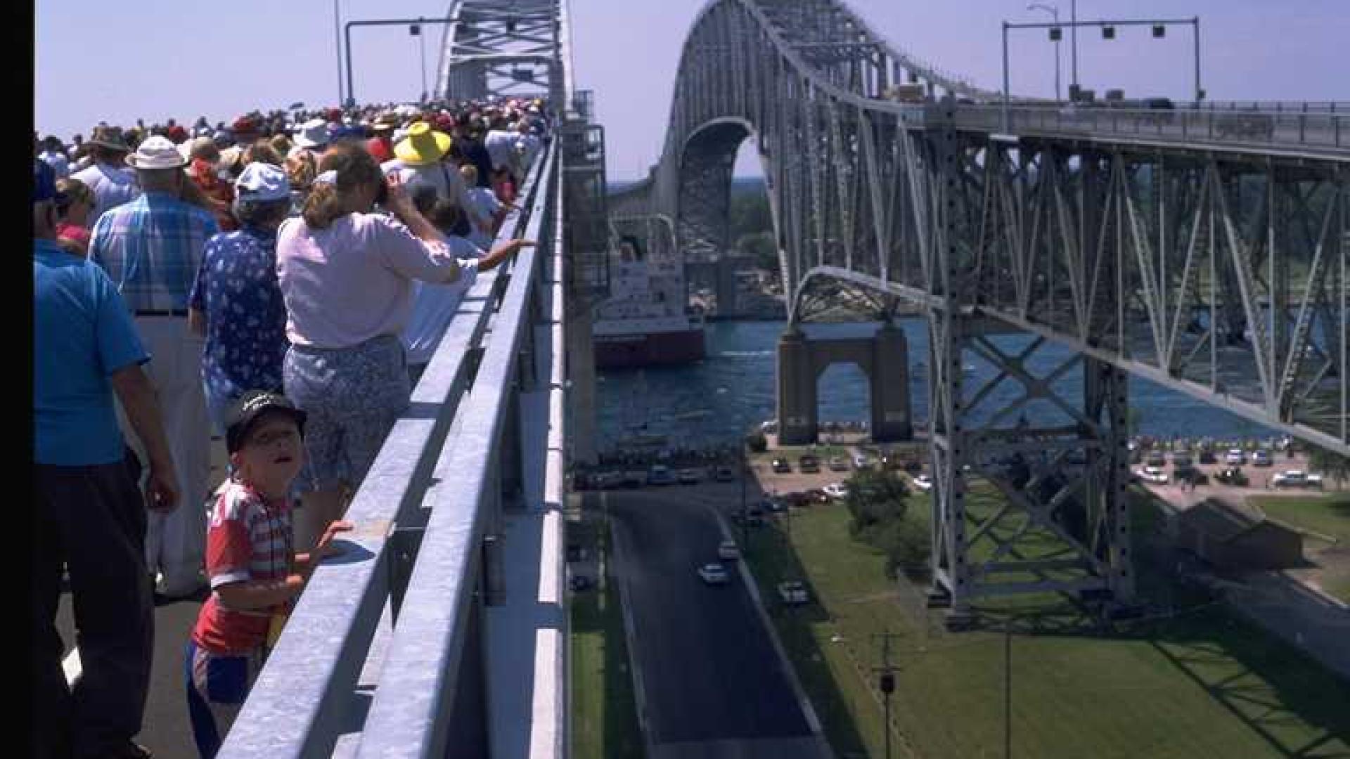 Massive group of people walking on one of the bridges. The other bridge is on the background.