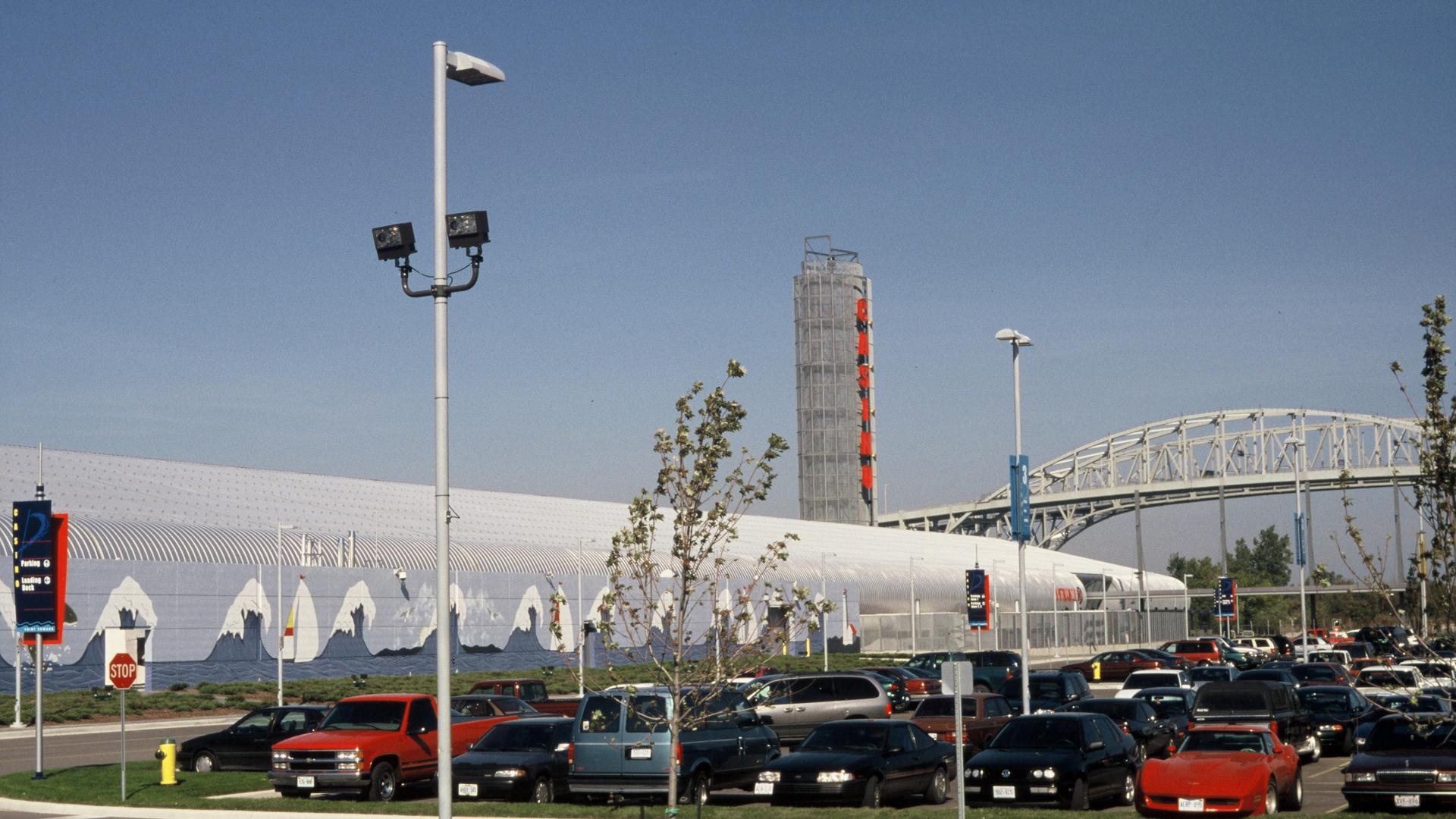 Parking lot in the foreground with bridge and building in the background.