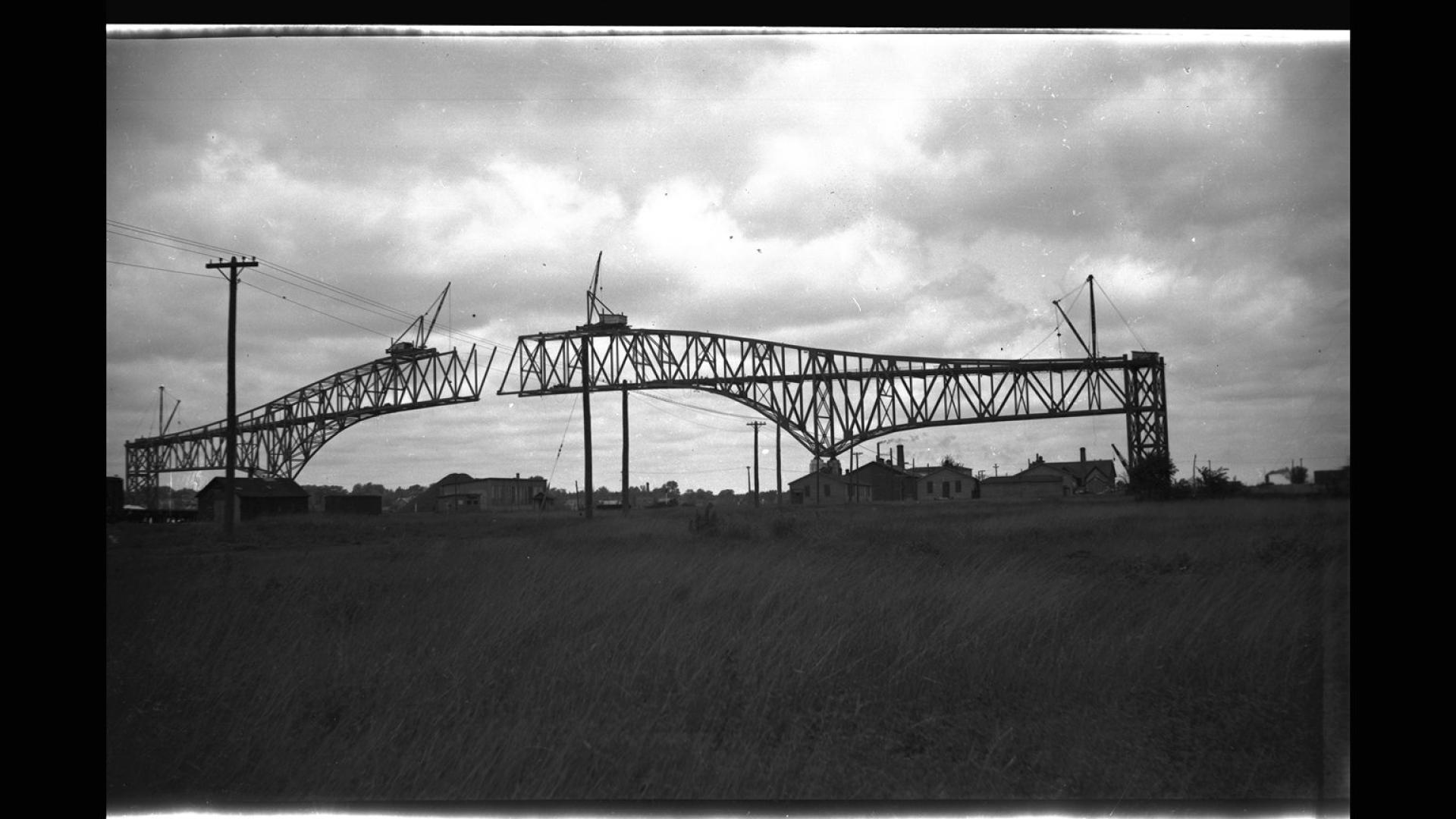 Silhouette of bridge under construction. There are clouds in the background. 