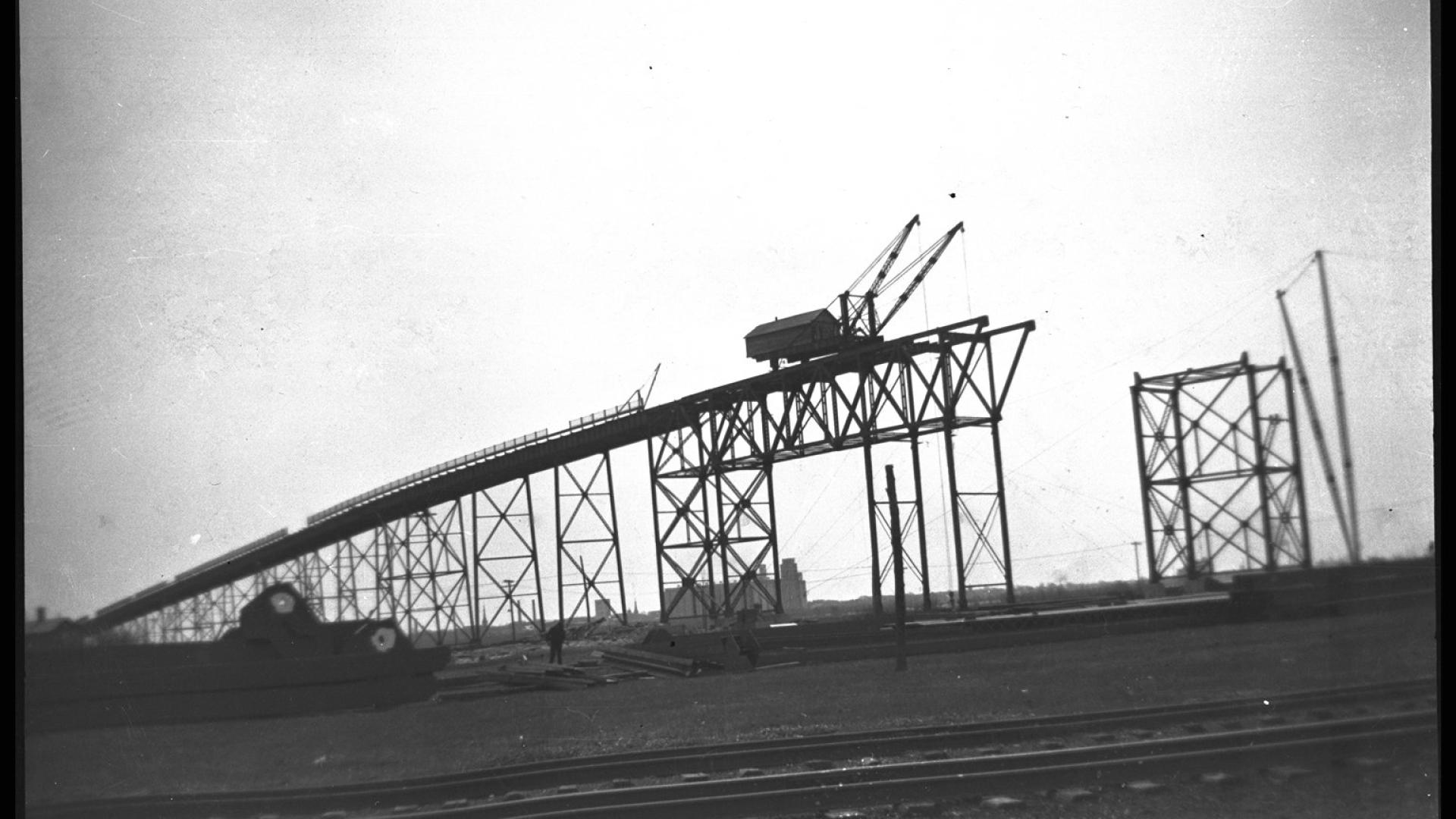 Silhouette of crane on bridge constructing bridge.