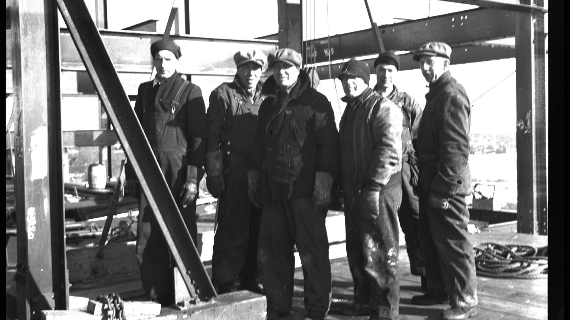 Group of men on bridge construction site.