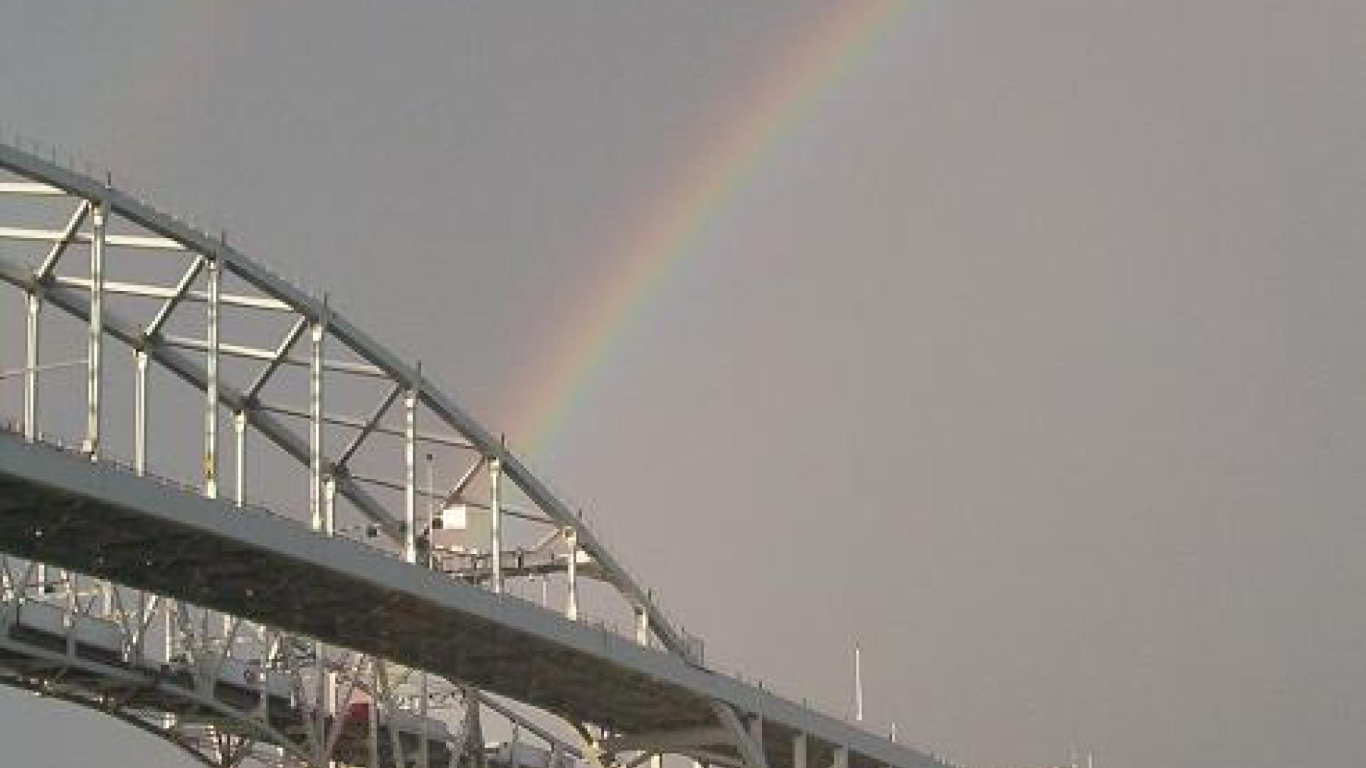 Rainbow arcing behind tall bridge.