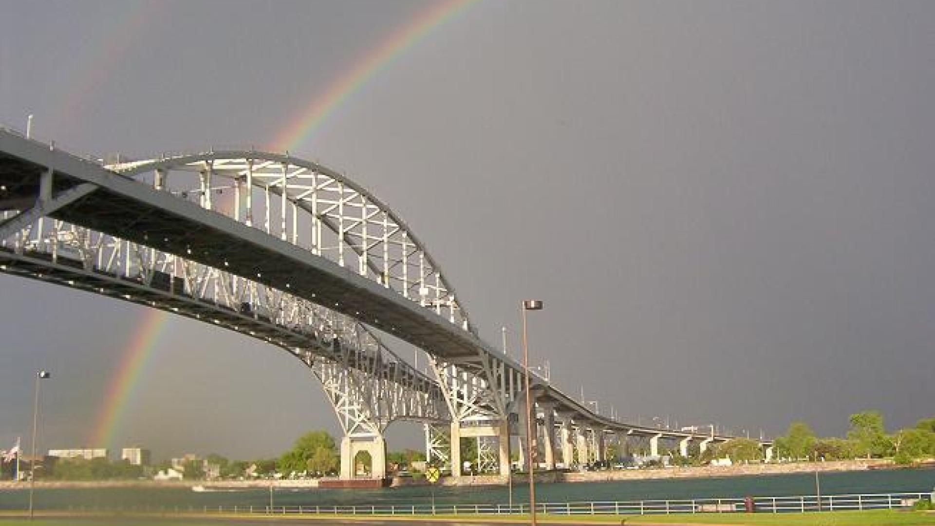 Rainbow arcing behind tall bridge.