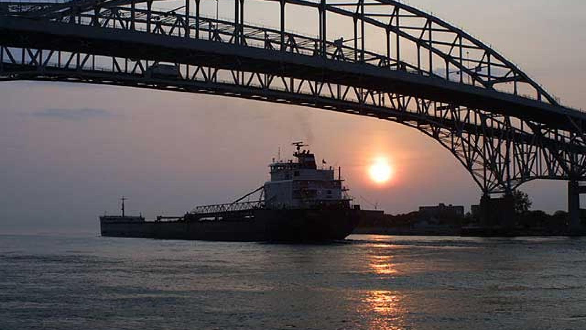 Silhouette of bridge standing tall in the foreground. In the background, the sun is glowing orange.