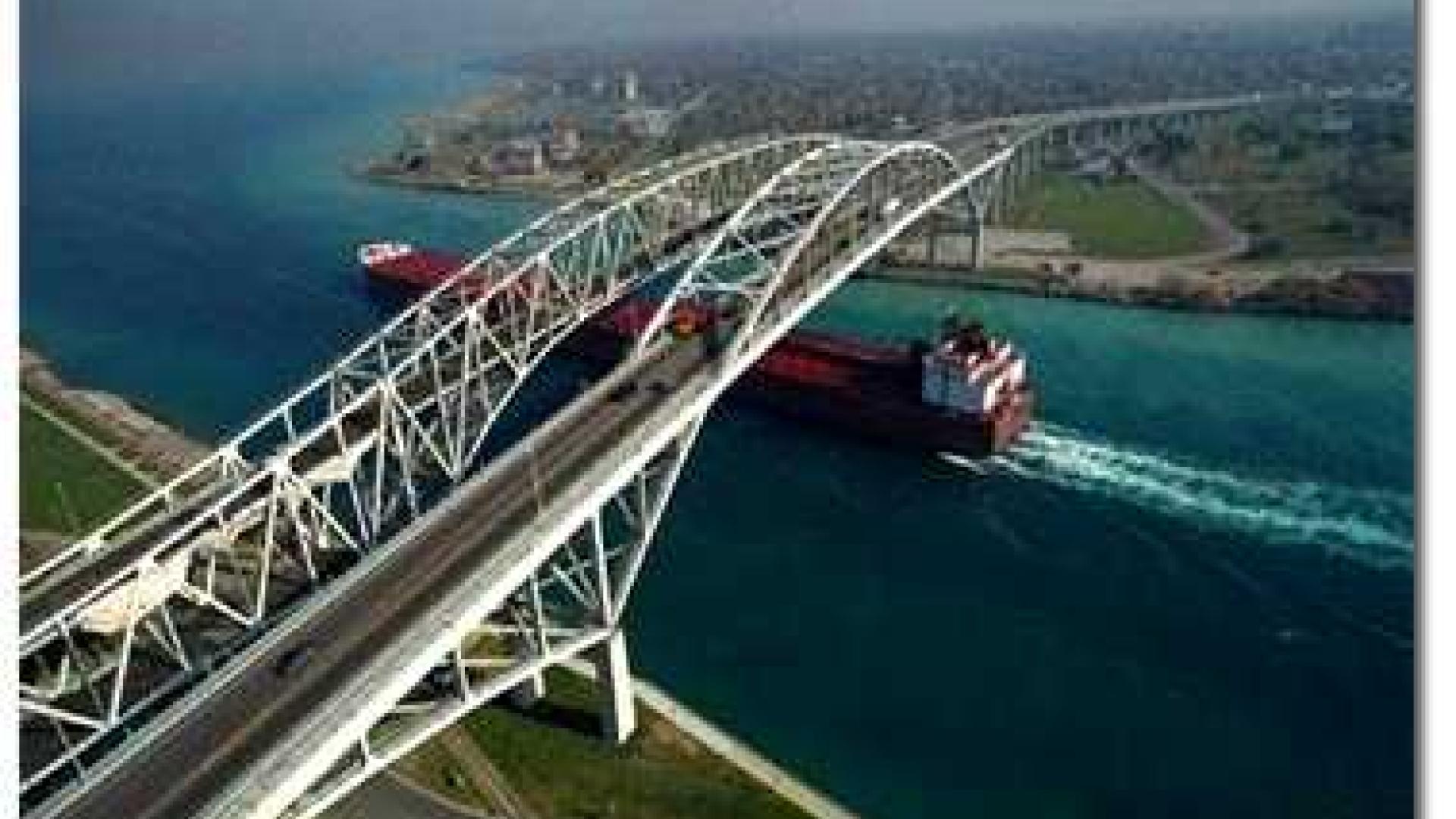 Aerial view of double bridge with a cargo bridge sailing under them.