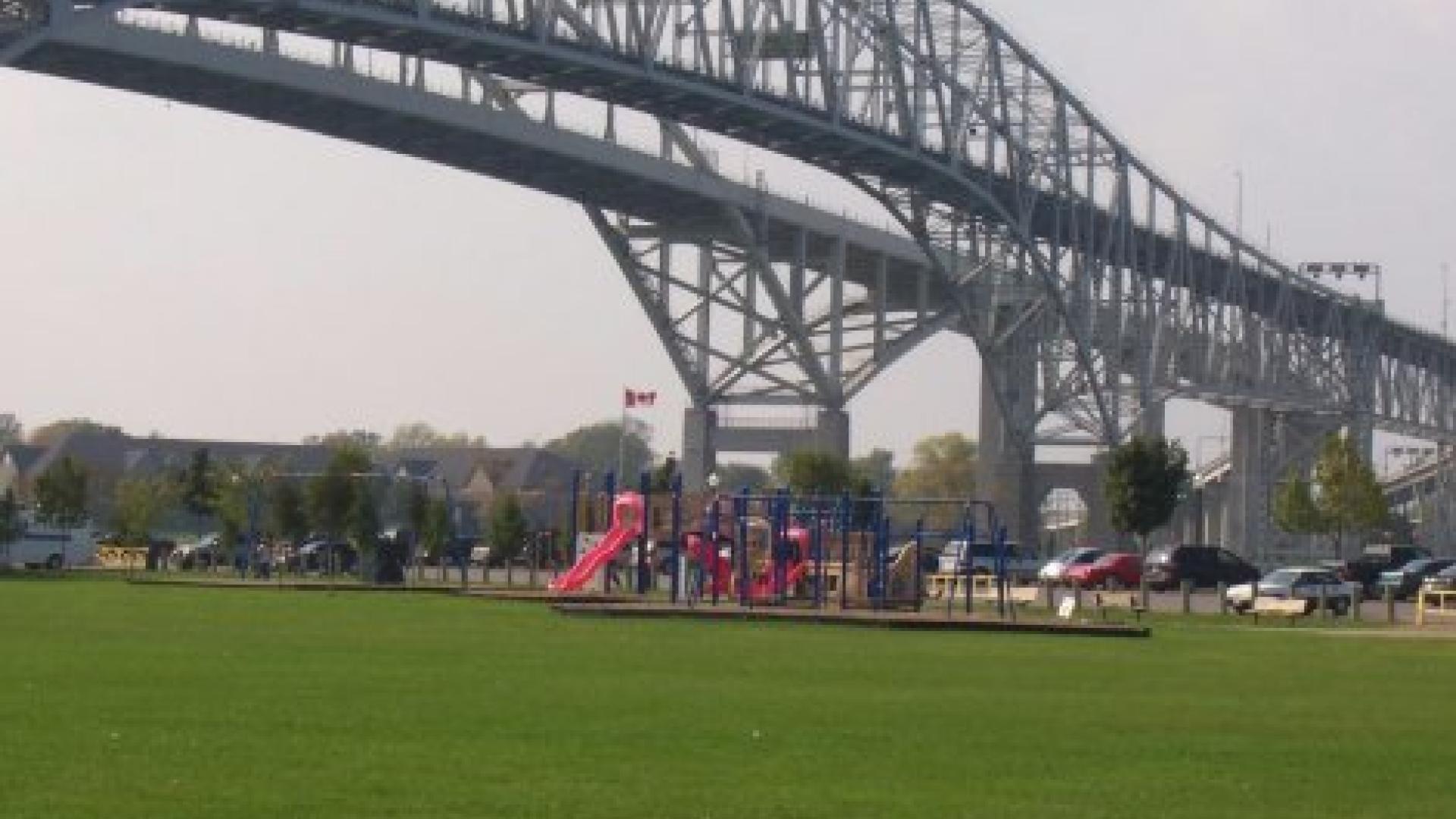 Small playground with a red jungle gym. There is a bridge in the background.