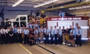 Fire crew posing in front of fire truck inside fire station. 
